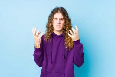 Uzun saçlı adam yalnız poz veriyor gergin elleriyle çığlık atıyor..