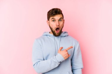 Pembe arka planda izole edilmiş genç beyaz adam yan tarafı gösteriyor.