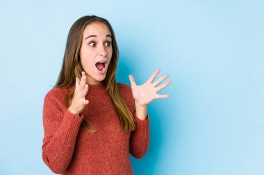 Yalnız poz veren beyaz kadın yüksek sesle bağırıyor, gözleri açık ve elleri gergin tutuyor..