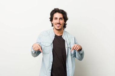 Beyaz bir geçmişi olan genç yakışıklı bir adam parmakları aşağıda, olumlu hisler içinde..