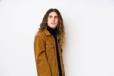 Uzun saçlı adam yalnız poz veriyor. Gülümsüyor, neşeli ve keyifli görünüyor..