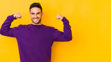 Beyaz tenli genç adam sarı fırında izole edilmiş. Güçlü bir hareket sergiliyor. Kadınsı gücün sembolü.