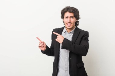 Beyaz bir arkaplan karşısında genç bir iş adamı işaret parmağıyla fotokopi alanını işaret ederek şok oldu..