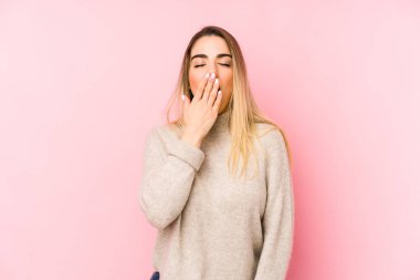 Orta yaşlı bir kadın izole edilmiş arka planda esniyor. Ağzı eliyle kapatan yorgun bir jest gösteriyor..