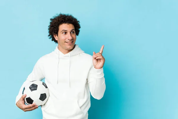 Sportowy Mężczyzna Trzymając Piłkę Nożną Uśmiecha Się Radośnie Wskazując Palcem — Zdjęcie stockowe