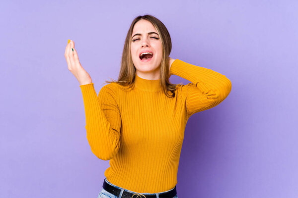 Young caucasian woman isolated on purple background screaming with rage.