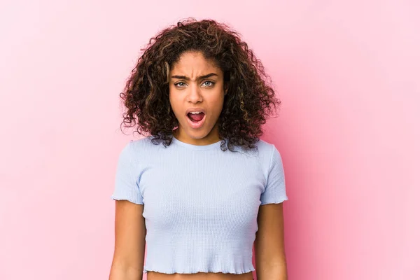 ピンクの背景に対する若いアフリカ系アメリカ人女性は非常に怒って攻撃的に叫ぶ — ストック写真