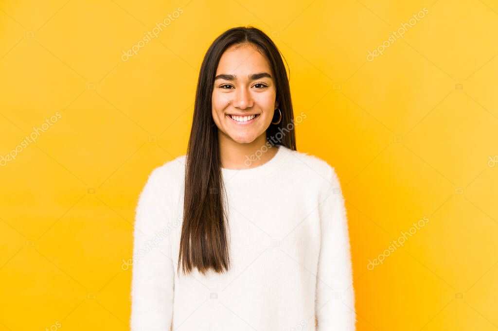 Young woman isolated on a yellow background happy, smiling and cheerful.