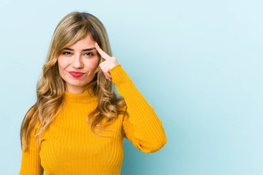 Sarışın, beyaz bir kadın şakağı parmağıyla işaret ediyor, düşünüyor ve bir göreve odaklanıyor..