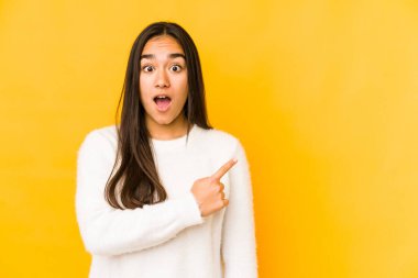 Sarı arka planda izole edilmiş genç bir kadın yan tarafı işaret ediyor.