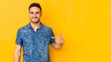 Beyaz tenli genç, sarı fırında izole edilmiş. Elle bir gömleğin fotokopi odasını işaret ediyor.