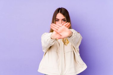 Mor arka planda izole edilmiş genç beyaz kadın inkar jesti yapıyor.