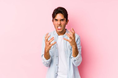 Pembe arka planda poz veren genç beyaz adam gergin elleriyle çığlık atıyor..