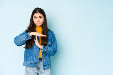 Mavi arka planda izole edilmiş genç Hintli kadın bir mola hareketi gösteriyor..