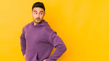 Sarı fırında izole edilmiş genç beyaz adam gülümseyen, neşeli ve keyifli bir tarafa bakıyor..