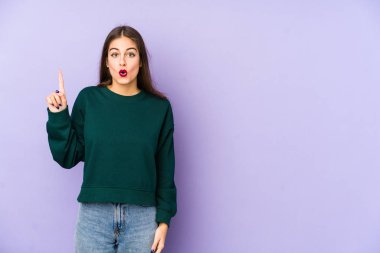 Mor arka planda izole edilmiş beyaz bir kadın ağzı açık bir şekilde üst tarafı işaret ediyor..