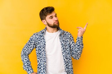 Sarı arka planda izole edilmiş genç beyaz adam sanki seni davet ediyormuş gibi seni işaret ediyor..