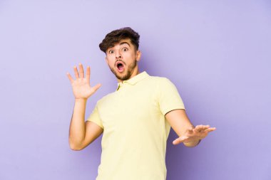 Mor arka planda izole edilmiş genç bir Arap yakın bir tehlike nedeniyle şoka uğruyor.