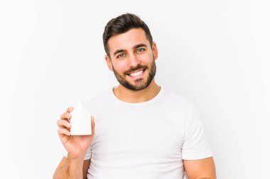 Elinde vitamin şişesi olan genç beyaz bir adam izole edilmiş mutlu, güler yüzlü ve neşeli..