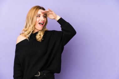 Sarışın genç kadın yalnız başına uzaklara bakıyor ve elini alnına koyuyor..