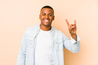Genç latin adam bej arka planda izole edilmiş boynuzları devrim konsepti olarak gösteriyor..