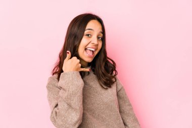 Genç melez İspanyol kadın izole edilmiş, parmaklarıyla bir cep telefonu hareketi gösteriyor..