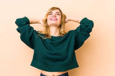 Sarışın, beyaz, kendinden emin, elleri başının arkasında olan bir kadın..