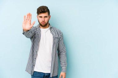Mavi arka planda izole edilmiş genç beyaz adam elini uzatmış, dur işareti göstererek seni engelliyor..