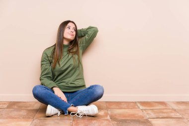 Genç, beyaz bir kadın yerde tek başına oturuyor. Kafasının arkasına dokunuyor, düşünüyor ve bir seçim yapıyor..