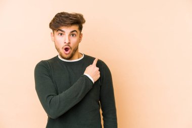 Bej arka planda izole edilmiş genç bir Arap yan tarafı işaret ediyor.