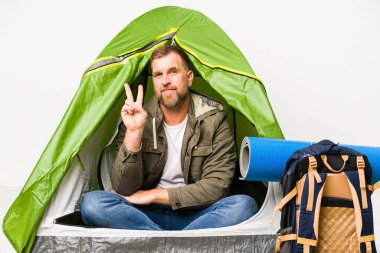 Senior beyaz arka planda izole bir çadırda iki numaranın parmaklarını gösteriyor..