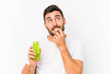 Genç, beyaz bir adam, elinde aloe vera ile nemlendirici tutarken izole edilmiş bir şekilde bir şeyin fotokopi odasına baktığını düşünürken rahatlamış..