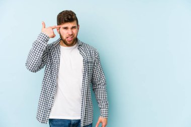 Mavi arka planda izole edilmiş genç beyaz adam işaret parmağıyla bir hayal kırıklığı jesti gösteriyor..