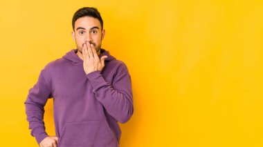 Sarı fırında izole edilmiş genç beyaz adam şok olmuş, ağzı ellerle kaplanmış, yeni bir şey keşfetmek için sabırsızlanıyor..