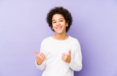 Afro-Amerikalı küçük çocuk kendini soyutlamış iki parmağını da kaldırıyor, gülümsüyor ve kendinden emin..