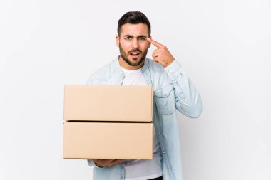 Genç, beyaz bir adam yeni evine taşınıyor işaret parmağıyla hayal kırıklığı jesti yapıyor..