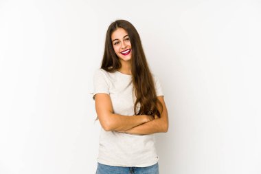 Beyaz arka planda kendini güvende hisseden, kararlılıkla kollarını kavuşturan beyaz tenli genç bir kadın..