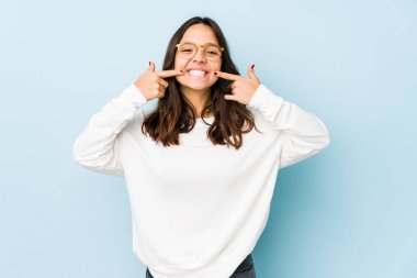 Genç, melez, ispanyol bir kadın. Tek başına gülüyor, parmaklarını ağzına doğrultuyor..