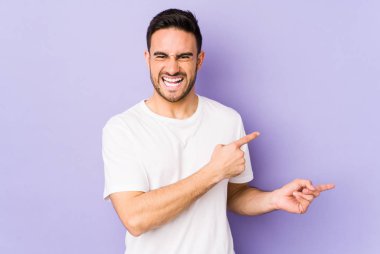 Mor arka planda izole edilmiş genç beyaz adam işaret parmağıyla fotokopi alanını işaret ederek heyecan ve arzusunu ifade ediyor..