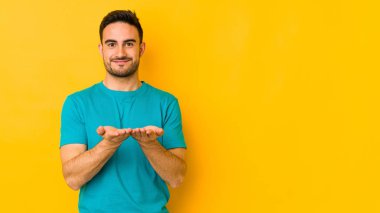 Kafkasyalı genç adam sarı fırında izole edilmiş. Elinde palmiyeli bir şey var ve kameraya sunuyor..