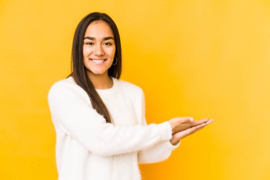 Sarı bir arka planda izole edilmiş genç bir kadın. Elinde bir kopyası var..