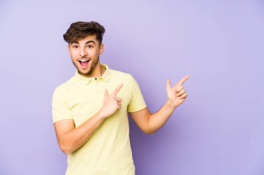 Mor arka planda izole edilmiş genç bir Arap adam işaret parmağıyla fotokopi alanını işaret ederek heyecan ve arzuyu ifade ediyor..