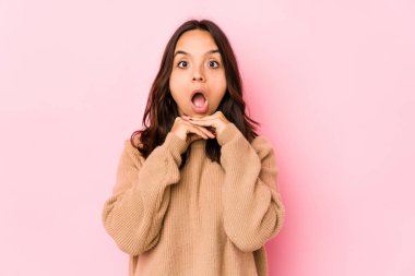 Genç, melez, Latin bir kadın yalnız başına şans diliyor, şaşırmış ve ağzı açık bir şekilde önüne bakıyor..