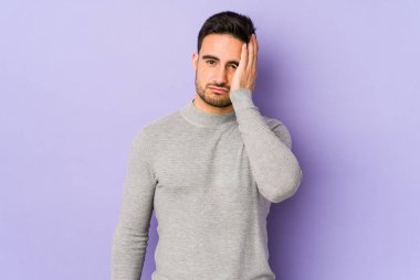 Mor arka planda izole edilmiş genç beyaz adam yorgun ve uykulu ellerini başının üstünde tutuyor..