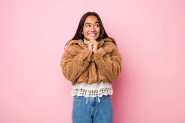 Koyun derisi paltosu giyen genç Hintli kadın ellerini çenesinin altına koyuyor ve mutlu bir şekilde yan tarafa bakıyor..