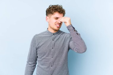 Sarışın, kıvırcık saçlı, beyaz tenli bir adam izole edilmiş, başı ağrıyor, yüzüne dokunuyor..