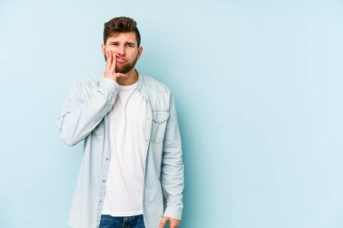 Mavi arka planda izole genç beyaz adam güçlü bir diş ağrısı, azıdişi ağrısı var..