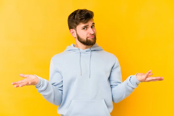 Joven Hombre Caucásico Aislado Sobre Fondo Amarillo Dudando Encogiéndose Hombros —  Fotos de Stock