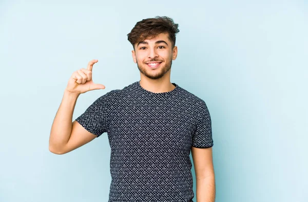 Young Arabian Man Isolated Blue Background Holding Something Little Forefingers — Stock Photo, Image