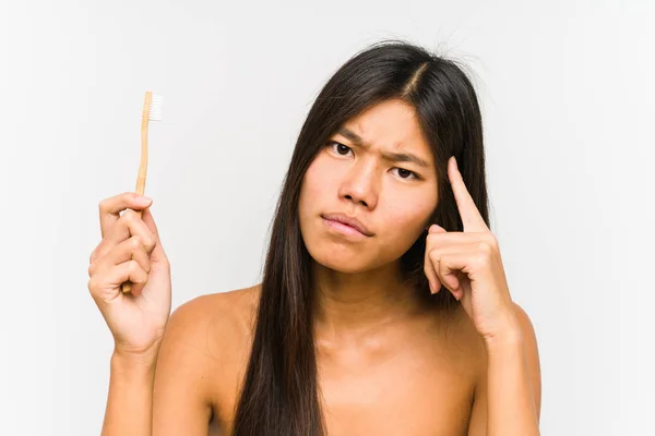 年轻的中国女人拿着牙刷 用手指 专心致志地把自己的太阳穴隔开了 — 图库照片